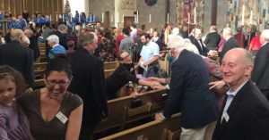the congregation shaking hands and greeting each other across the pews