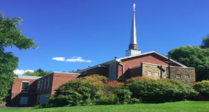 The First Congregational Church building, made of red brick with a tall white steeple