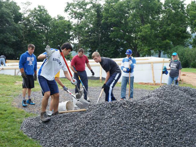 Seven people with shovels digging or spreading gravel