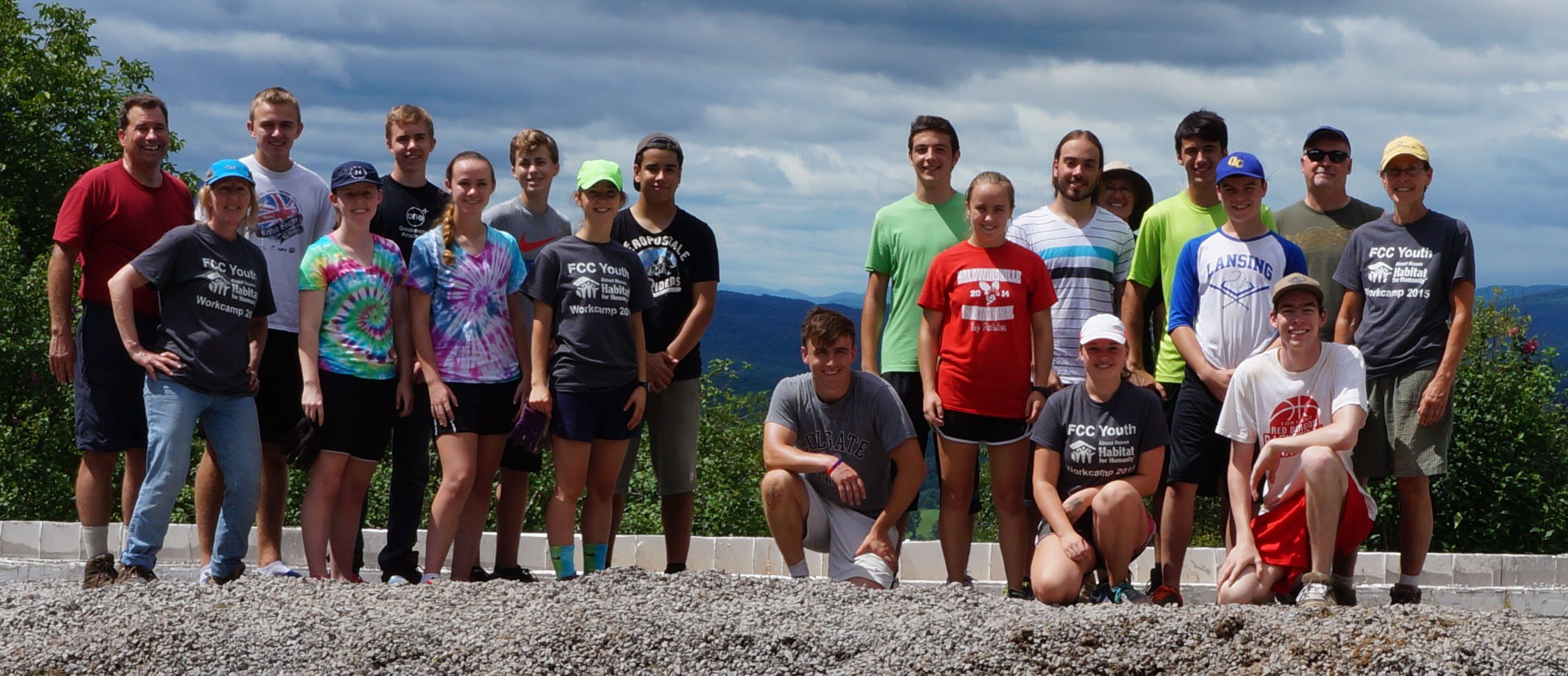 20 youth and adults posing in rows at a Habitat for Humanity build site