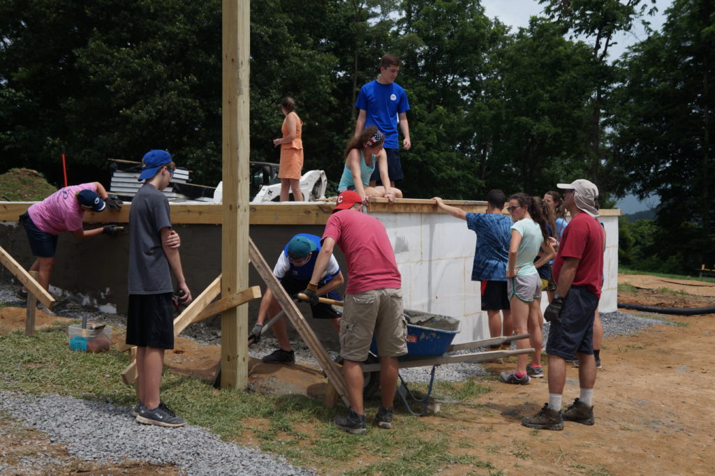 Eleven people working on various aspects of the foundation of a Habitat for Humanity home