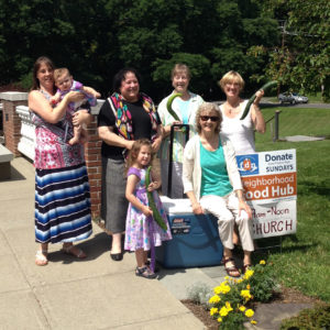 Five adults and two children on the church patio with the Food Hub donation cooler