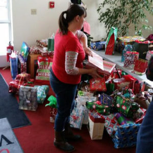 A church member in front of a room full of gifts for the Giving Tree, to be donated to organizations serving children and families