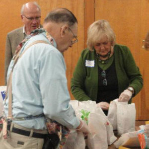 Three congregation members assembling lunches for the Friendship Center