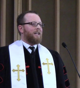 Sr. Minister David Kaden at pulpit in black robes and white stole