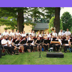 the Ithaca Concert Band members outside with their instruments on a grassy field